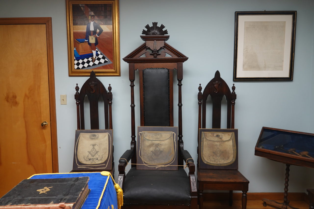 Framed Masonic aprons displayed on lodge chairs